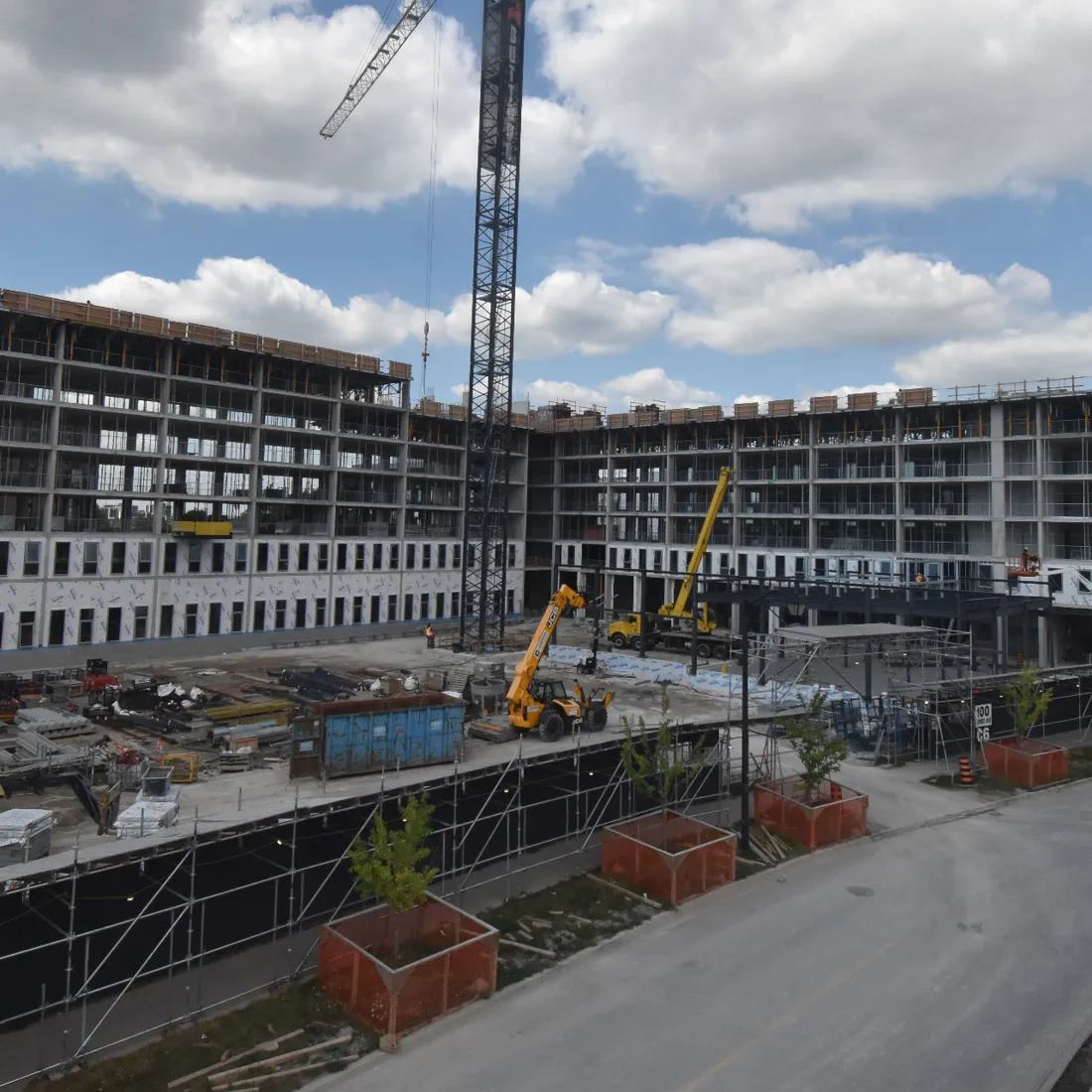Long curved mid-rise structure with a crane and plant along the site road