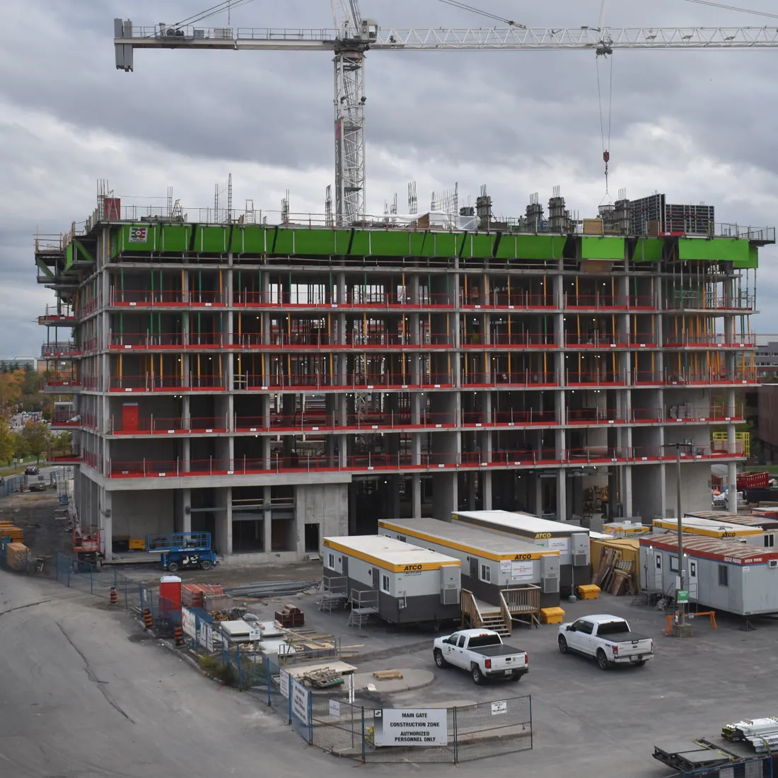 Mid-rise building topped out, with site trailers and parking below